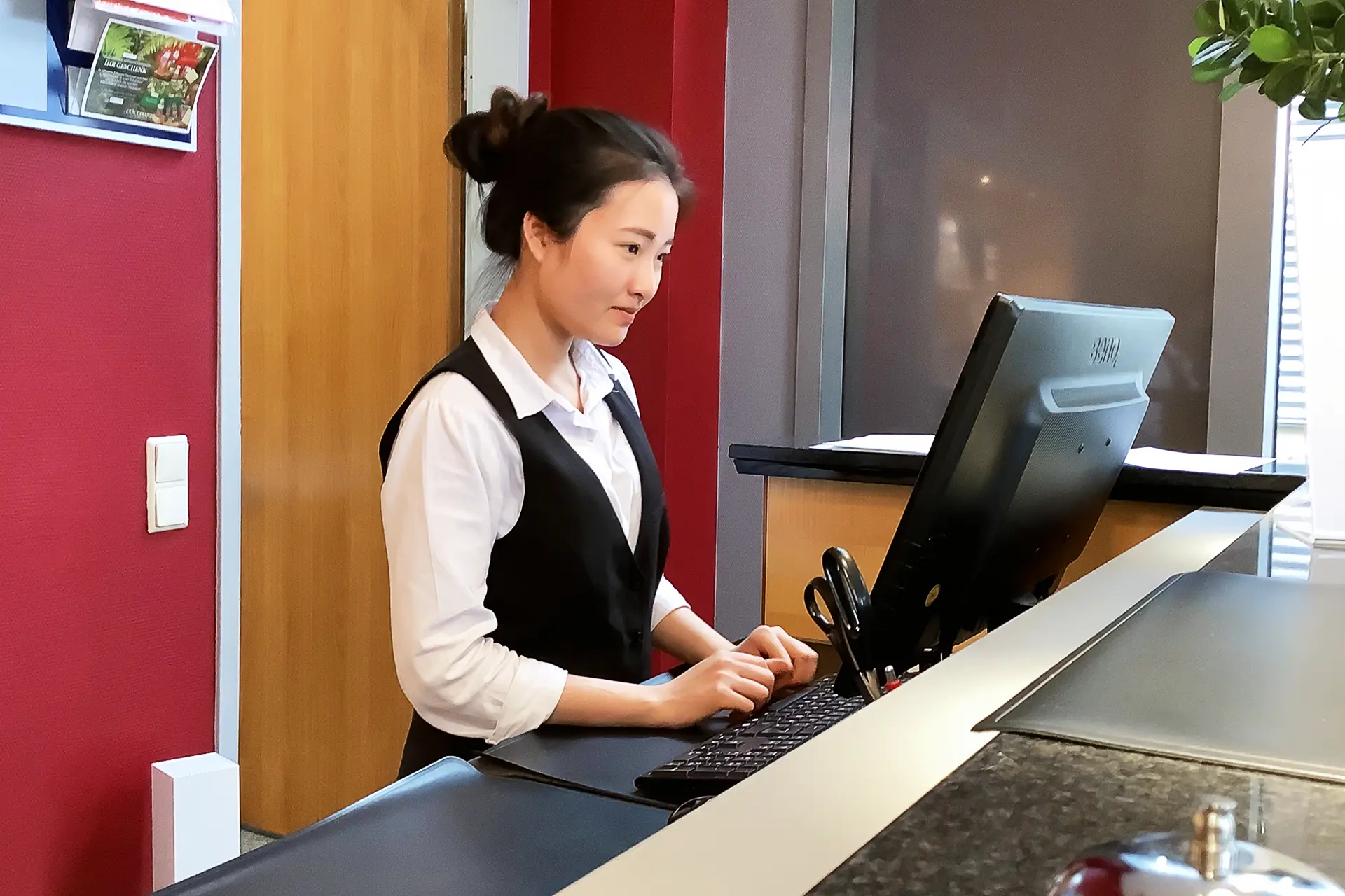 junge Frau an Rezeption - Ausbildung Hotelfachmann / Hotelfachfrau (HoFa-Ausbildung)