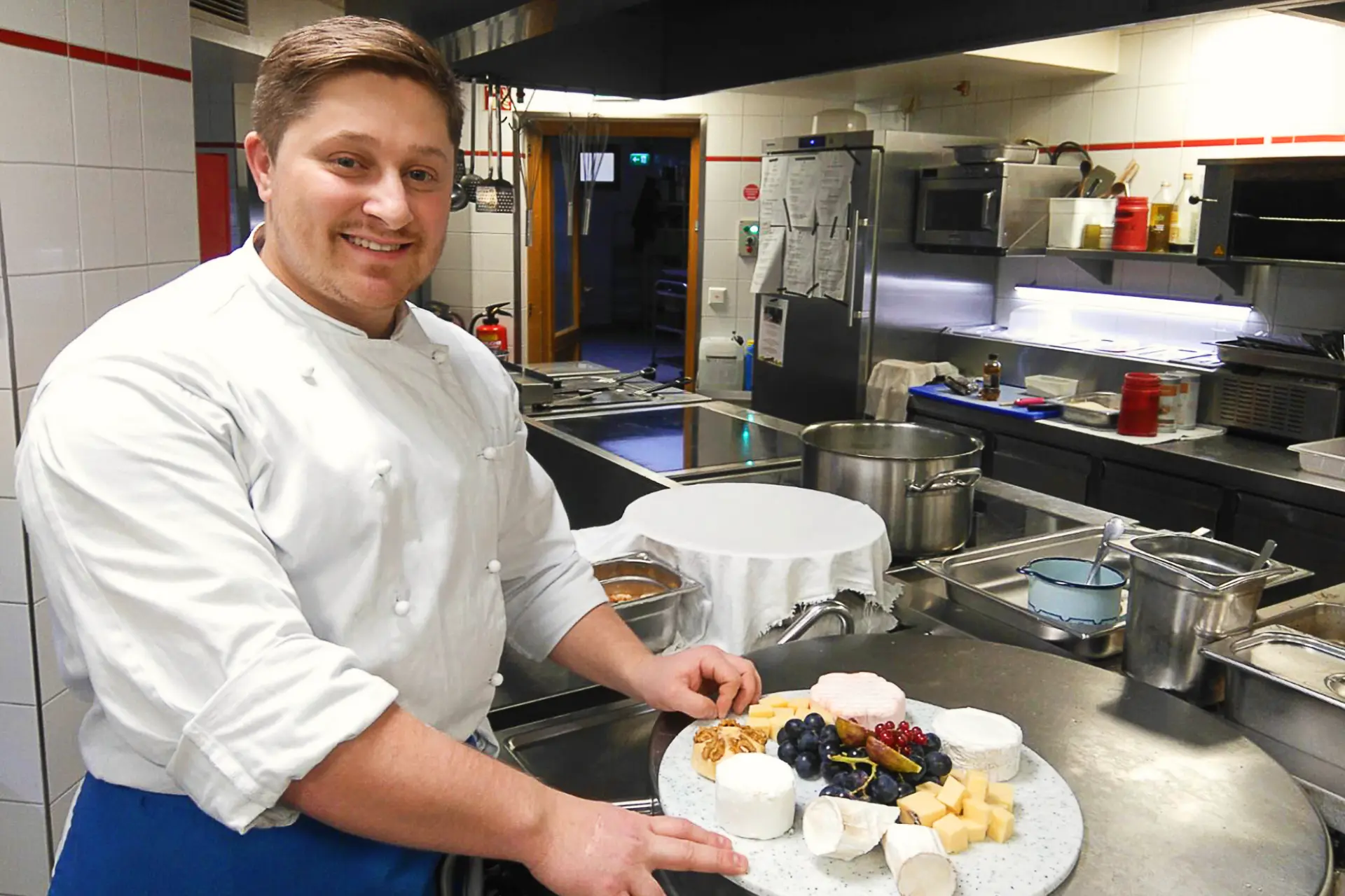 Koch mit Käseplatte in Küche - Berufsausbildung Koch / Köchin / Koch-Ausbildung
